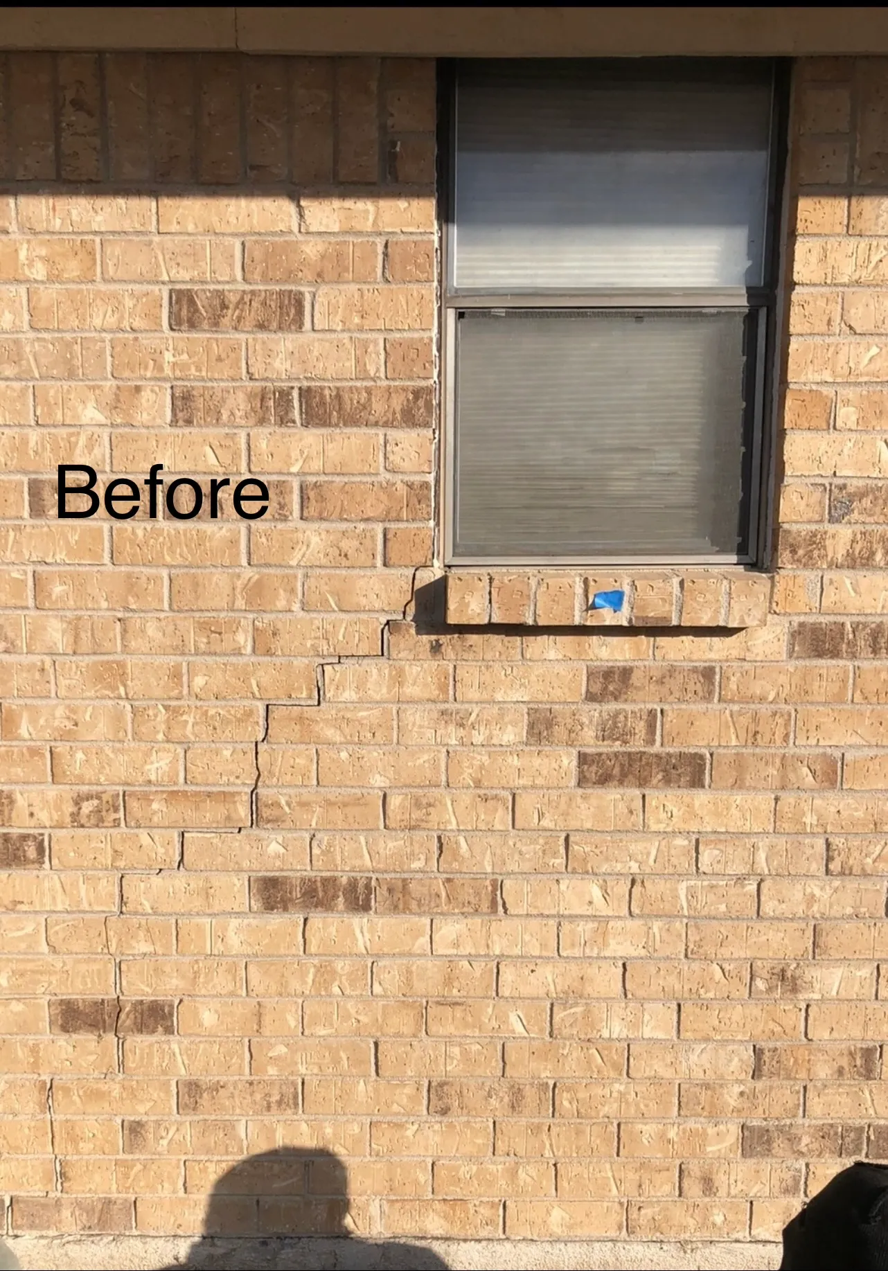A stair-step crack running down the brick beneath a window before A-Custom Foundation Repair