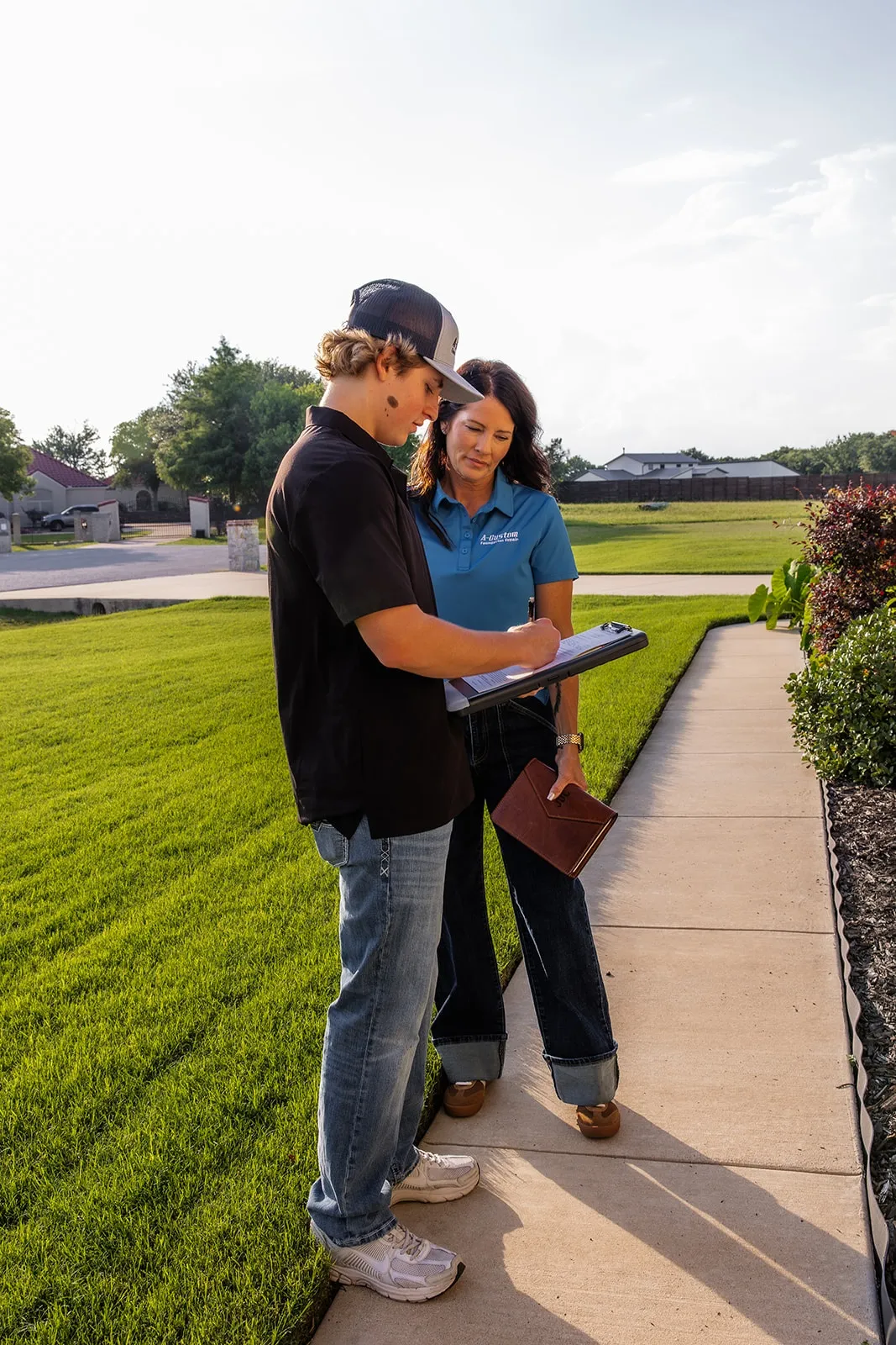 An A-Custom Foundation Repair team member writing up a free foundation quote with a homeowner outside their home